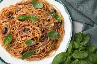 Delicious pasta with anchovies, tomato sauce and basil on table, top view