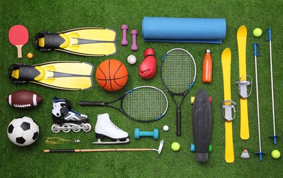 Photo of Different sport equipment on green grass, flat lay