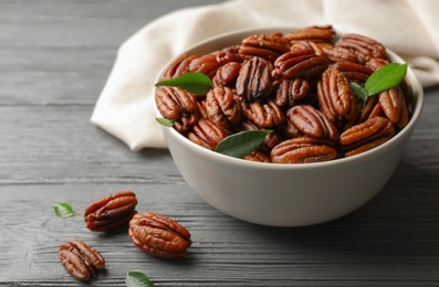 Photo of Dish with tasty pecan nuts on wooden table