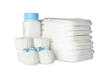 Photo of Disposable diapers, child's booties and bottle on white background