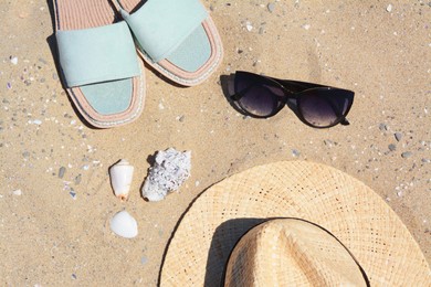 Photo of Stylish slippers, straw hat and sunglasses on sand, flat lay. Beach accessories