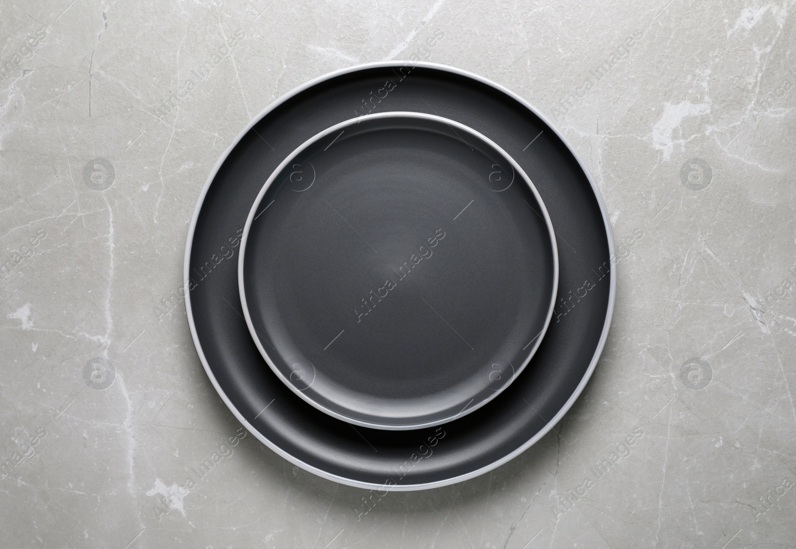 Photo of New dark plates on light grey table, top view