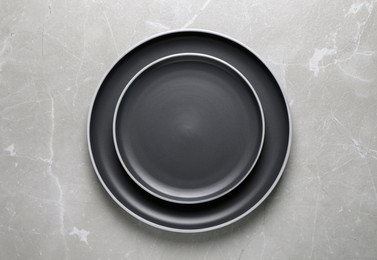 Photo of New dark plates on light grey table, top view