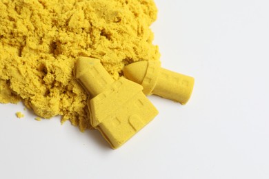 Photo of Castle and tower made of yellow kinetic sand on white background, top view