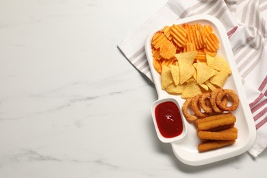 Photo of Different delicious fast food served with ketchup on white marble table, top view. Space for text
