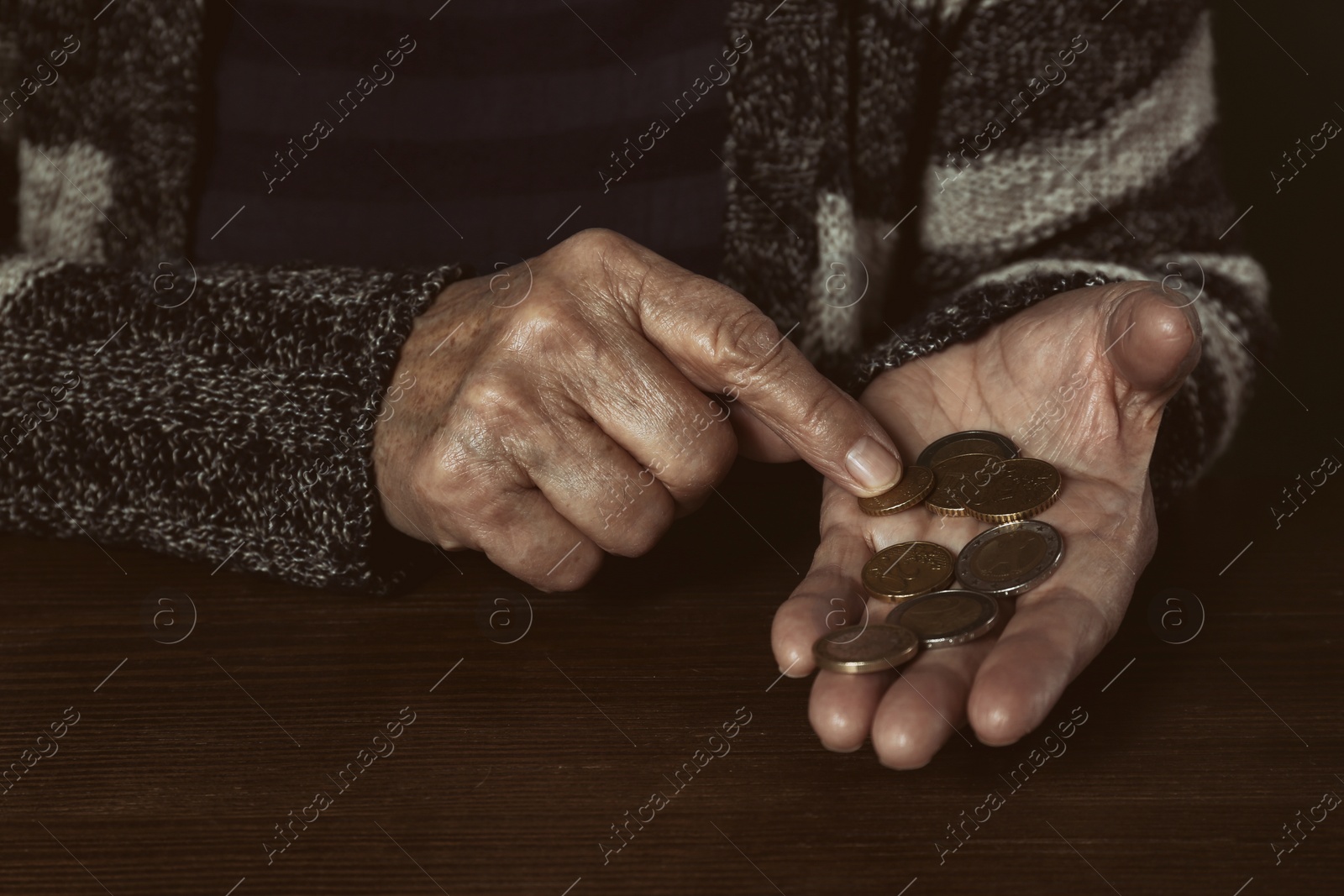 Photo of Poor senior woman with coins at table, closeup