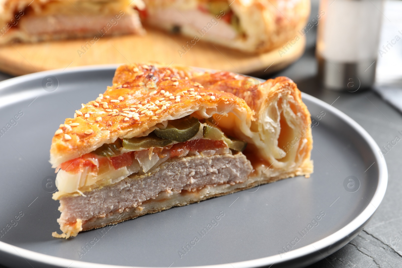 Photo of Piece of tasty homemade pie with filling on dark grey table, closeup