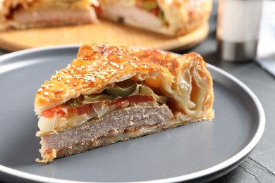 Photo of Piece of tasty homemade pie with filling on dark grey table, closeup