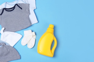 Photo of Flat lay composition with bottle of detergent and children's clothes on light blue background