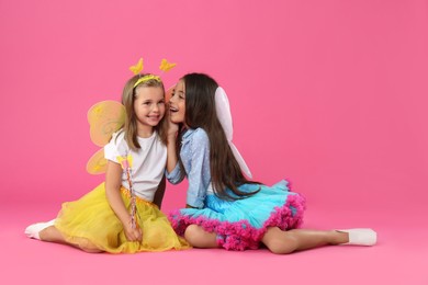 Photo of Cute little girls in fairy costumes with wings on pink background