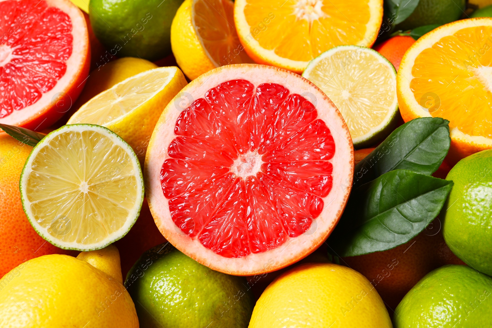 Photo of Different fresh citrus fruits and leaves as background, closeup