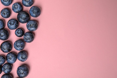 Photo of Tasty ripe blueberries on pink background, flat lay with space for text