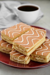 Photo of Tasty sponge cakes and hot drink on light grey table, closeup