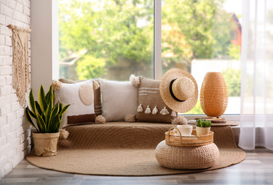 Photo of Comfortable place for rest with cushions near window indoors