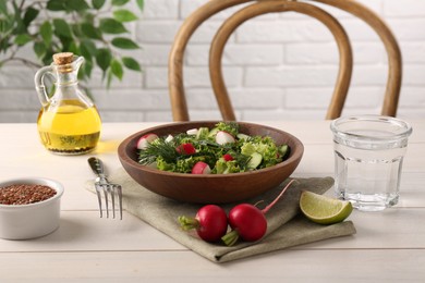 Delicious salad with radish, lettuce, dill and cucumber served on light wooden table, closeup