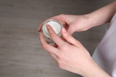 Woman applying hand cream indoors, above view