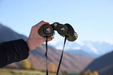 Photo of Boy holding binoculars in beautiful mountains on sunny day, closeup