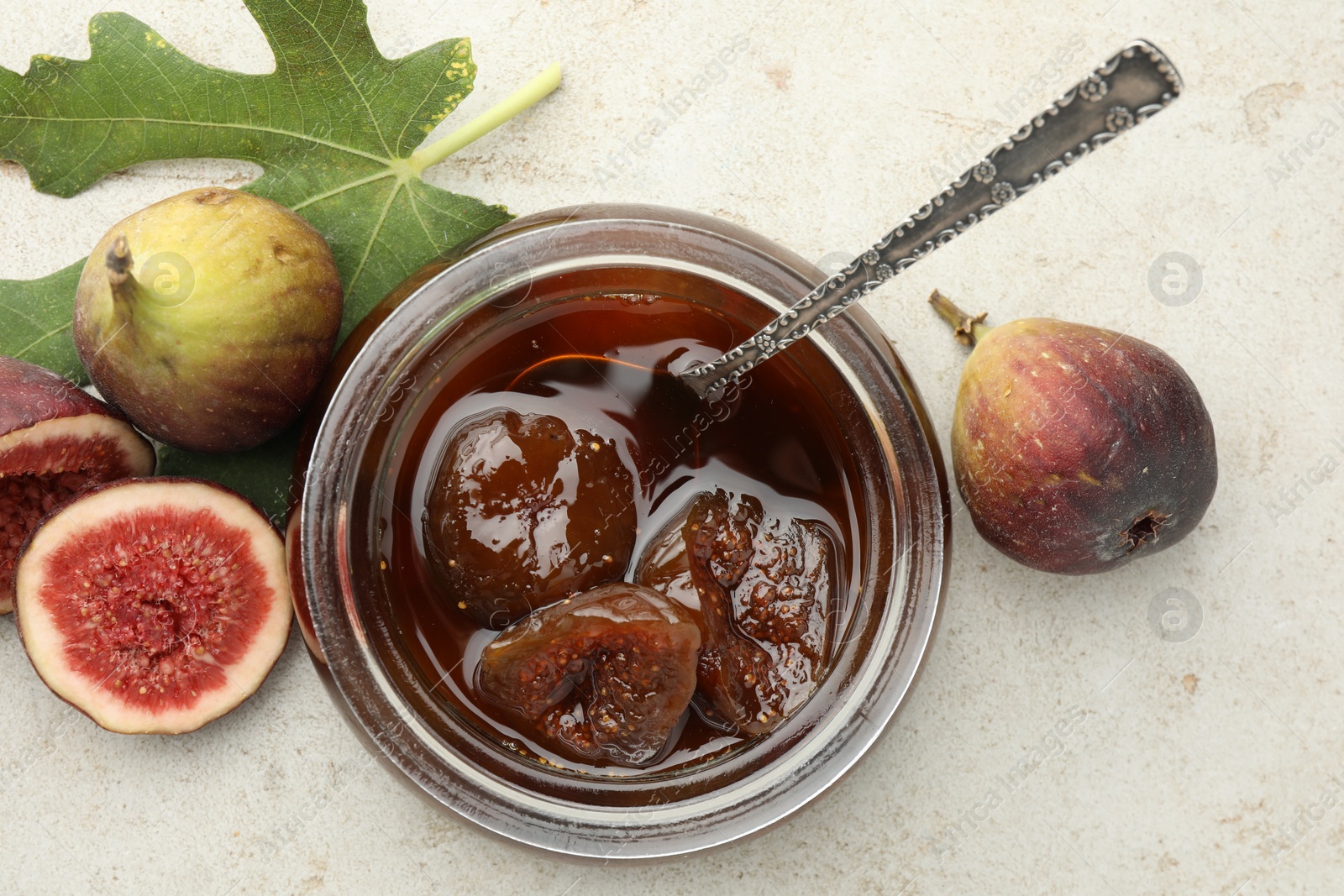 Photo of Jar of tasty sweet jam and fresh figs on white table, flat lay