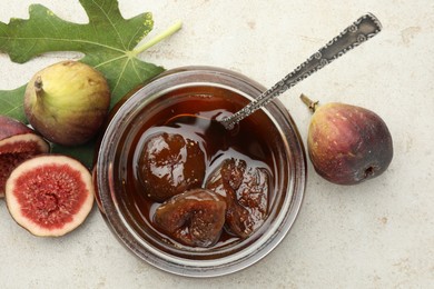 Jar of tasty sweet jam and fresh figs on white table, flat lay