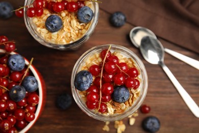 Delicious yogurt parfait with fresh berries on wooden table, flat lay