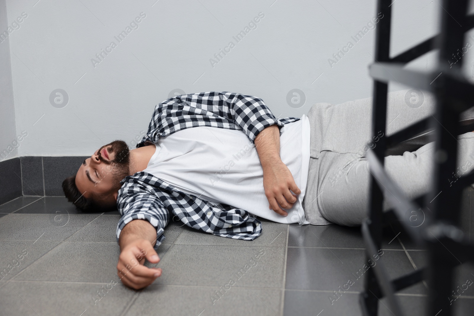 Photo of Unconscious man lying on floor after falling down stairs indoors