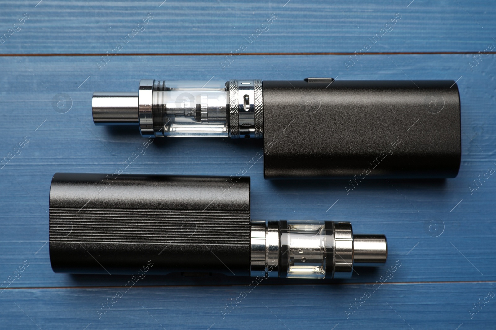 Photo of Electronic cigarettes on blue wooden background, flat lay