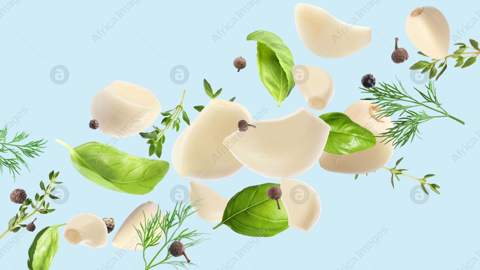 Image of Fresh peeled garlic cloves, peppercorns, and different herbs flying on light blue background