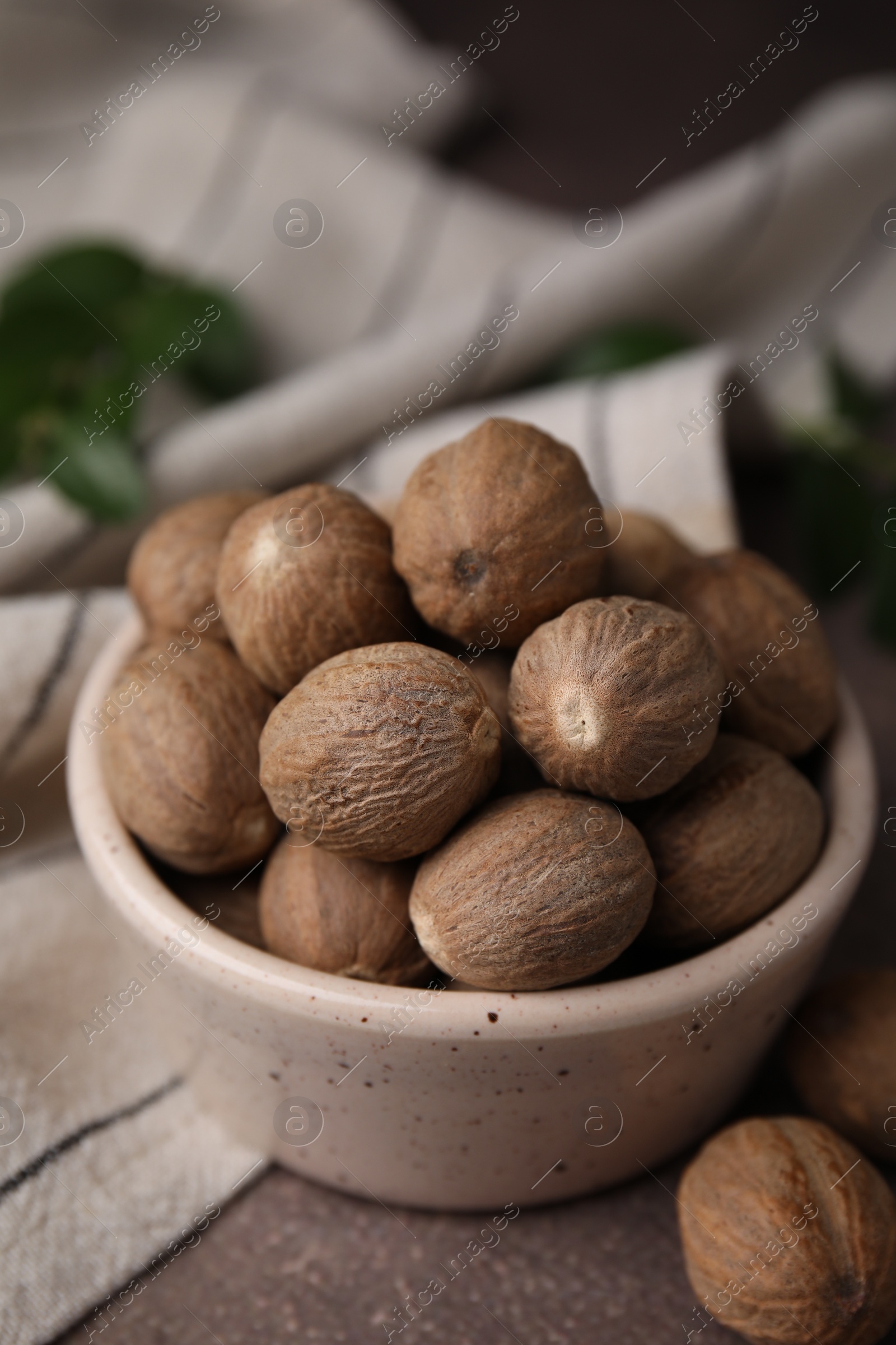 Photo of Whole nutmegs in bowl on brown table