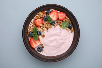 Photo of Bowl with yogurt, berries and granola on light grey background, top view