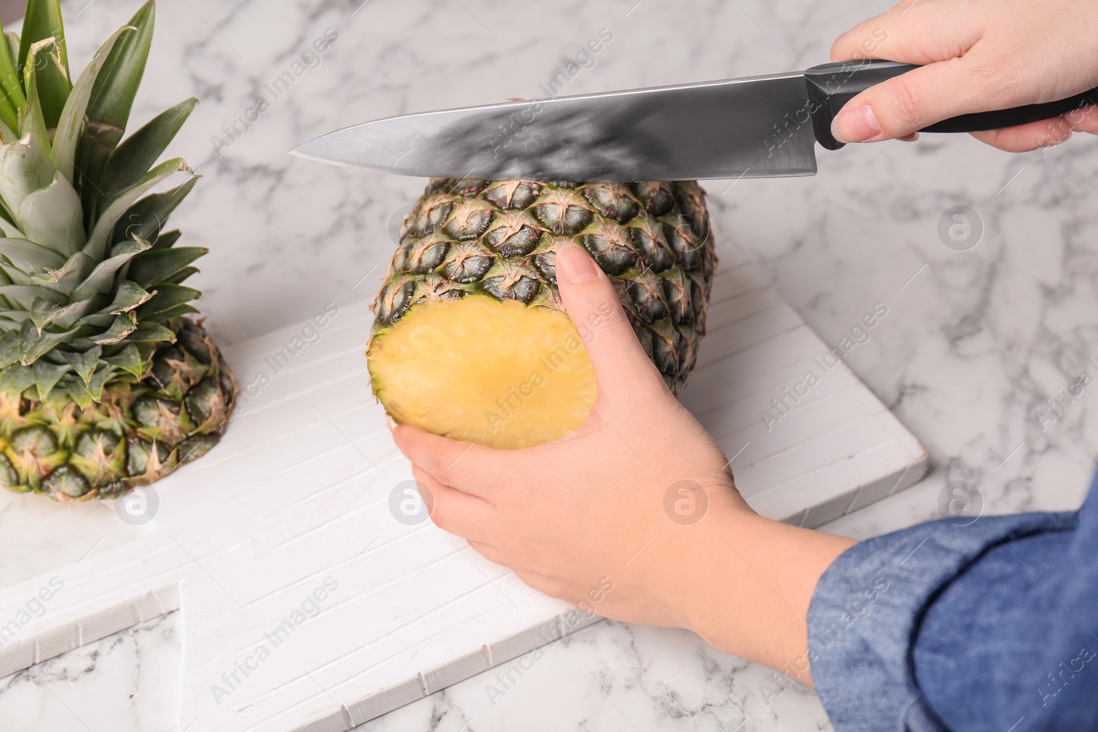 Photo of Woman cutting fresh pineapple on wooden board