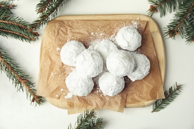 Photo of Christmas snowball cookies and fir tree branches on white table, flat lay