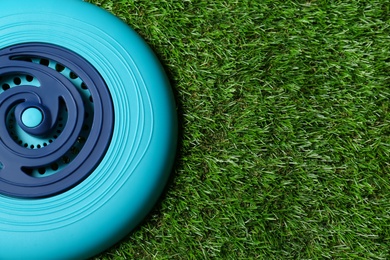 Photo of Light blue plastic frisbee disk on green grass, top view. Space for text