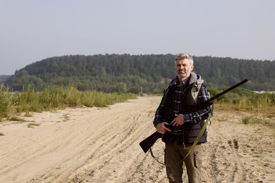 Photo of Man with hunting rifle outdoors. Space for text