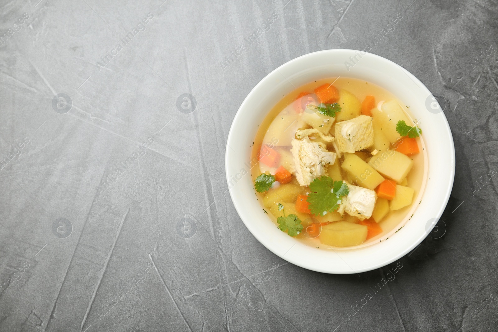 Photo of Homemade chicken soup in dish on grey background, top view with space for text