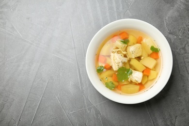 Photo of Homemade chicken soup in dish on grey background, top view with space for text