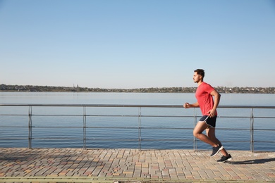 Sporty man running outdoors on sunny morning