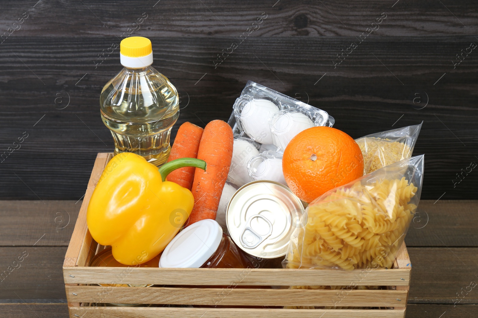 Photo of Crate with donation food on wooden table, closeup