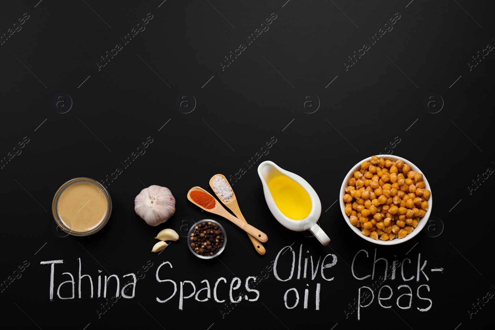 Photo of Delicious hummus, ingredients and chalk written products names on black background, flat lay. Space for text