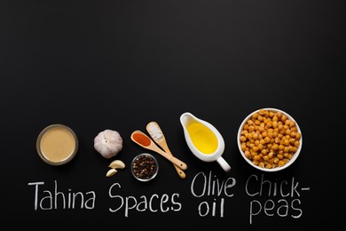 Photo of Delicious hummus, ingredients and chalk written products names on black background, flat lay. Space for text