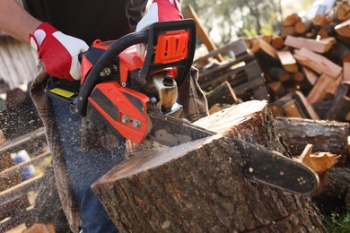 Man sawing wooden log outdoors, closeup view