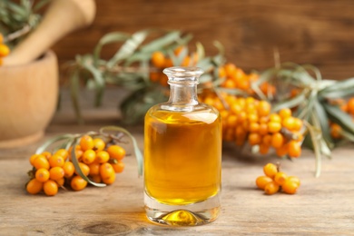 Photo of Natural sea buckthorn oil and fresh berries on wooden table