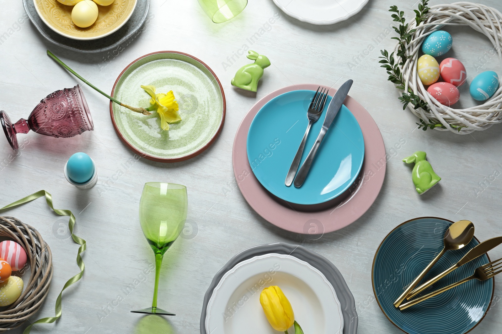 Photo of Festive Easter table setting with painted eggs on wooden background, top view