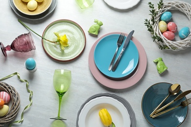 Festive Easter table setting with painted eggs on wooden background, top view