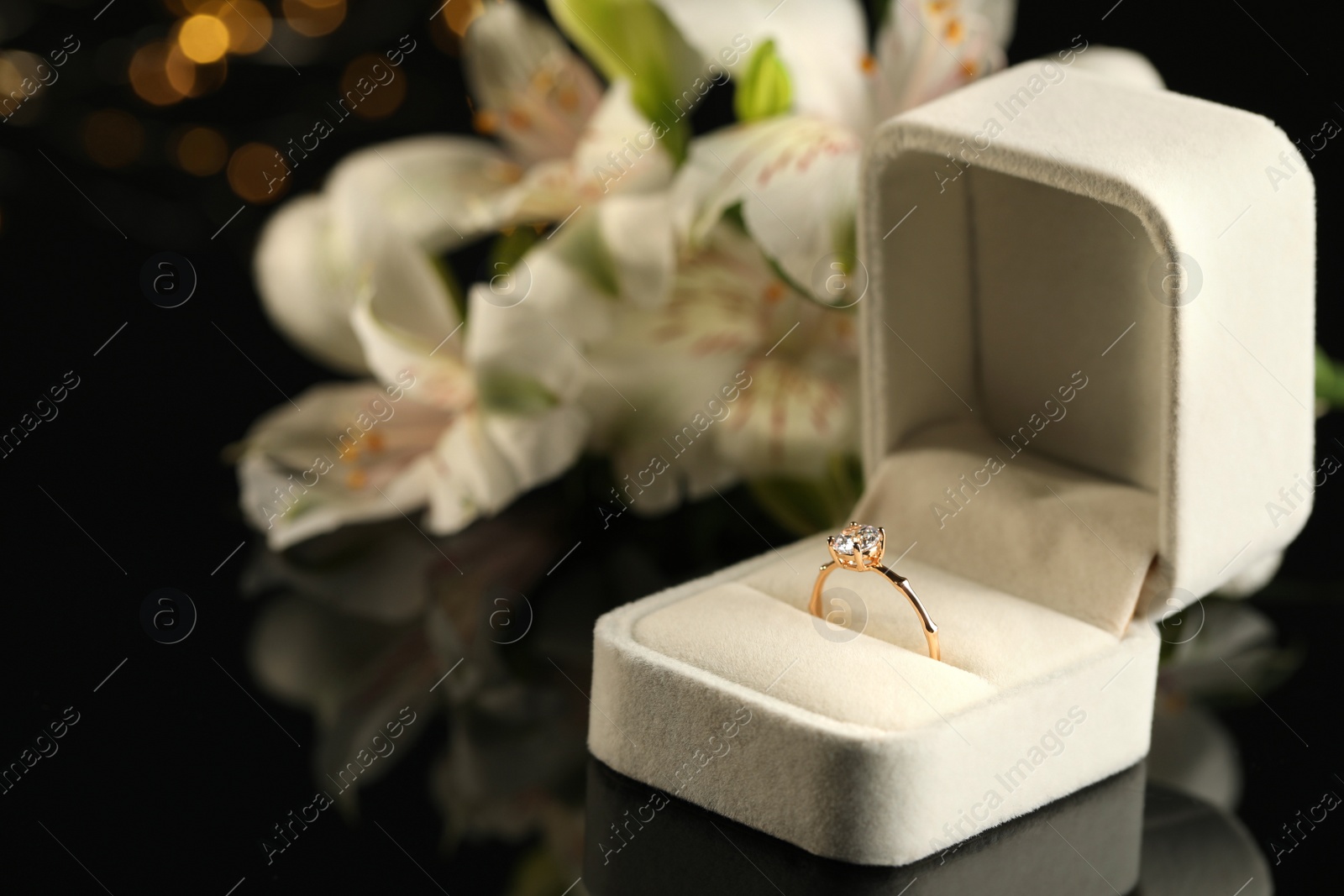 Photo of Beautiful engagement ring in box against blurred background, space for text