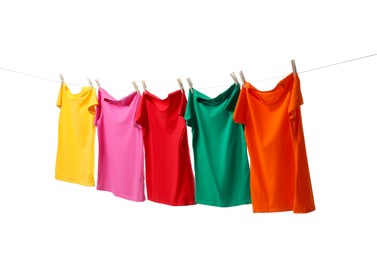 Different bright t-shirts drying on washing line against white background