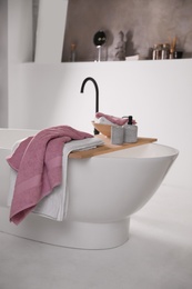 Image of Soap dispenser and soft towels on wooden board in bathroom. Interior design