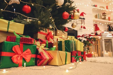 Many different gift boxes on floor near Christmas tree in room