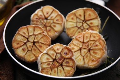Photo of Frying pan with fried garlic on table, closeup