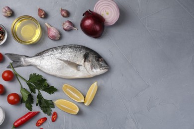 Photo of Flat lay composition with raw dorado fish and vegetables on grey table. Space for text
