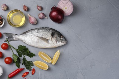 Flat lay composition with raw dorado fish and vegetables on grey table. Space for text